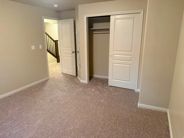 Neutral tone wall finishes, carpeting, and a built-in closet with sliding panel doors