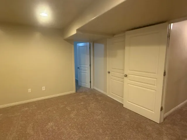 Recessed ceiling lighting, textured carpeting, neutral wall finishes, white trim, and a paneled door