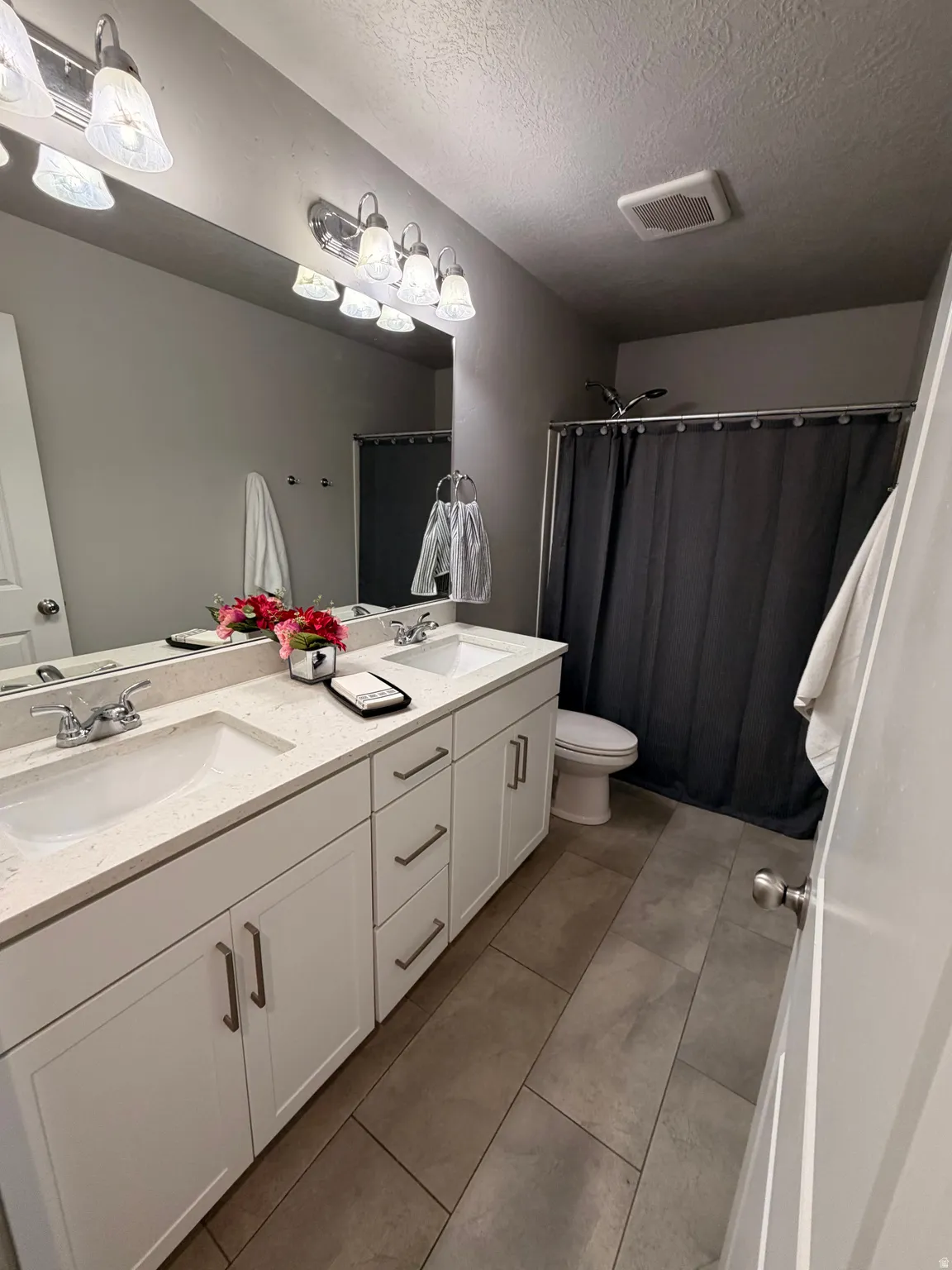 Spacious bathroom featuring a dual vanity with white cabinetry, light-toned countertops, and two undermount sinks