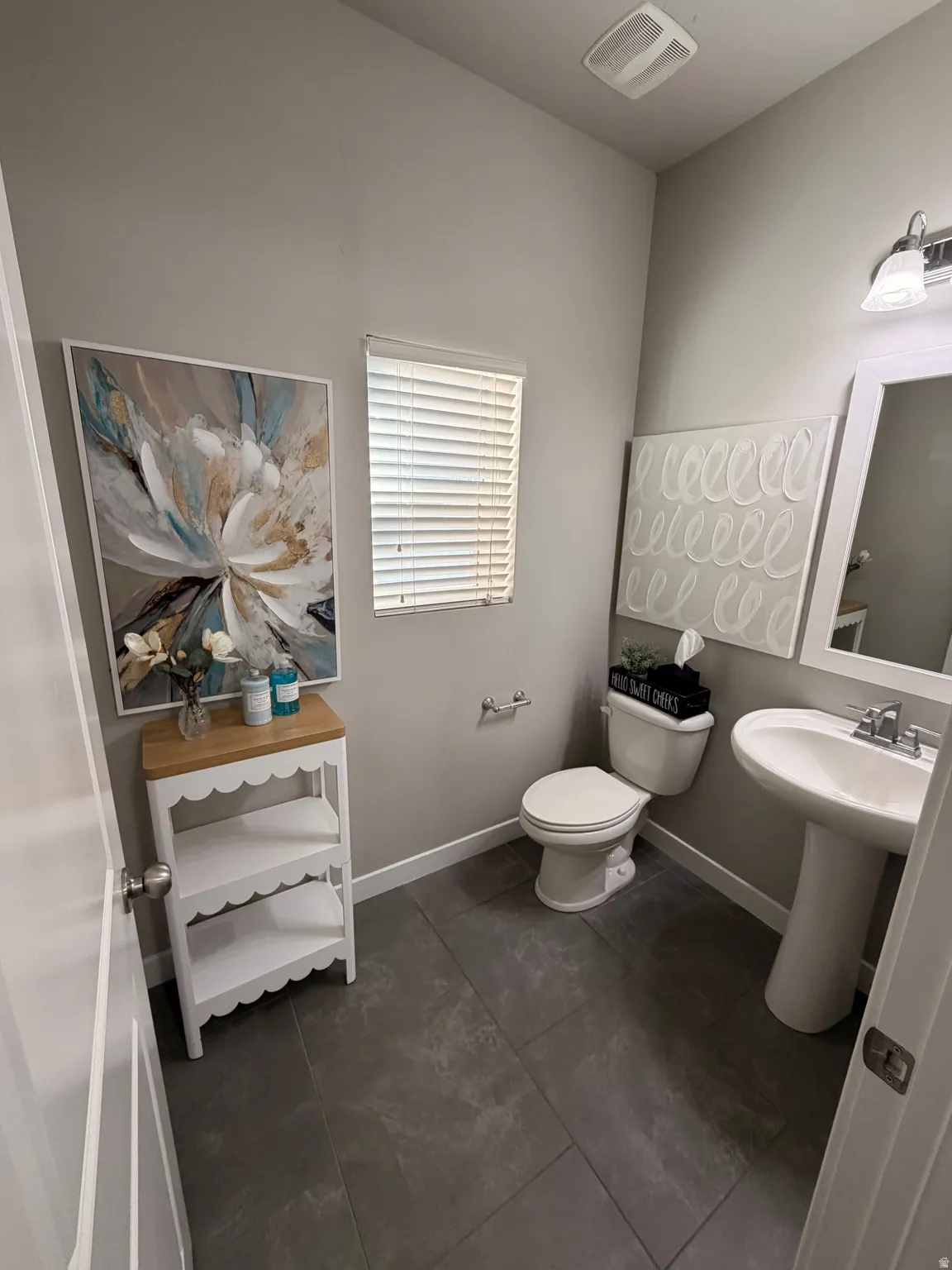Bathroom featuring dark tile flooring, a pedestal sink, and a window with blinds
