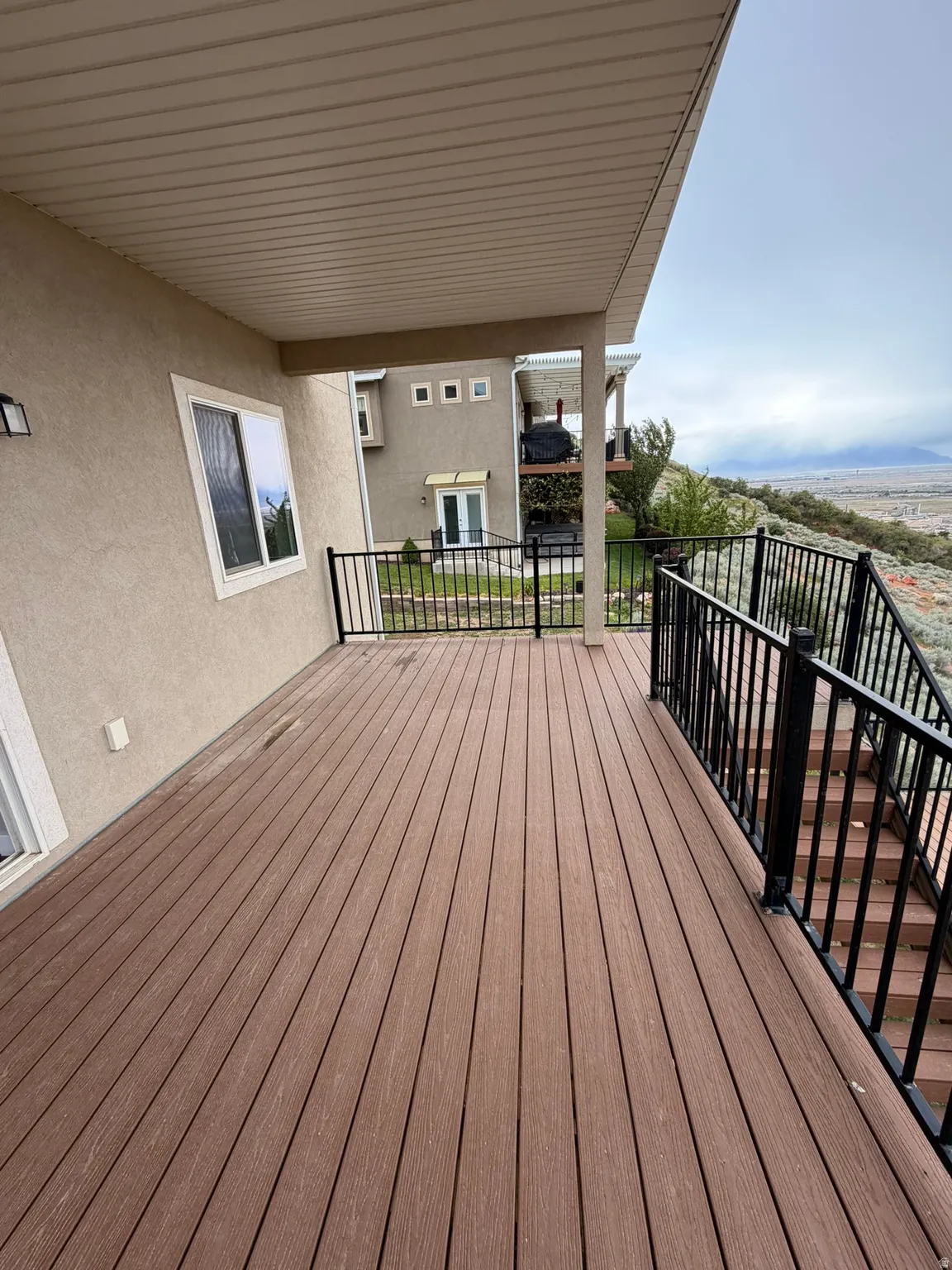 Expansive outdoor deck featuring wood-finish decking, black metal railings, and a covered ceiling