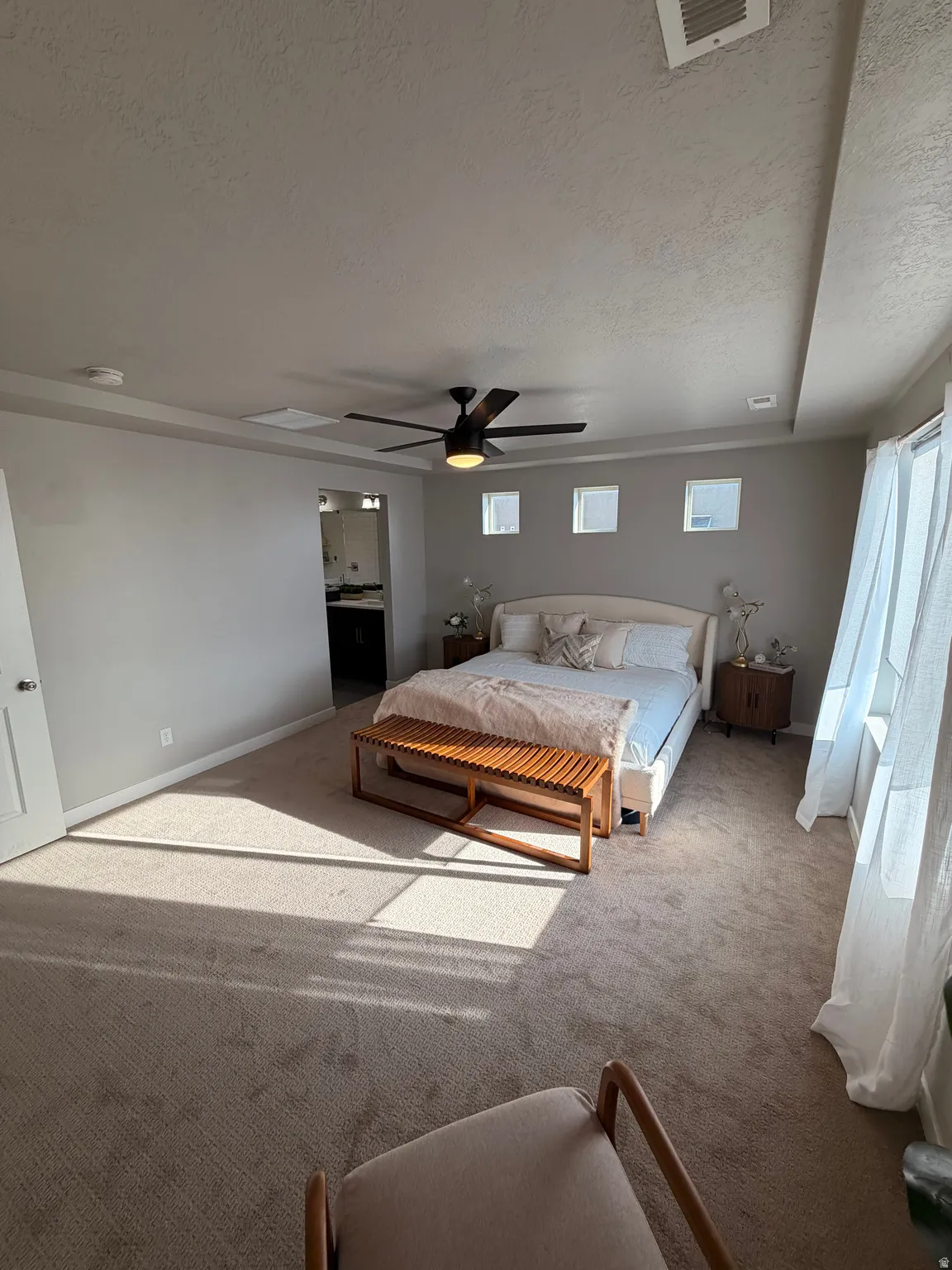 Spacious room featuring carpeting, a ceiling fan with integrated lighting, and multiple windows