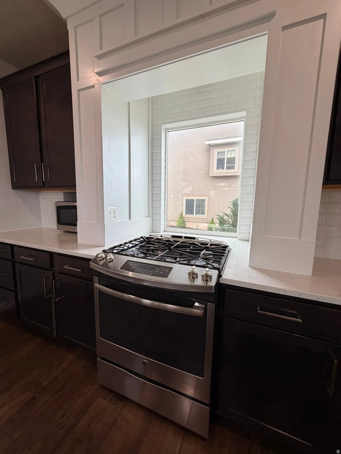 Stainless steel gas range with a tile backsplash and white countertops