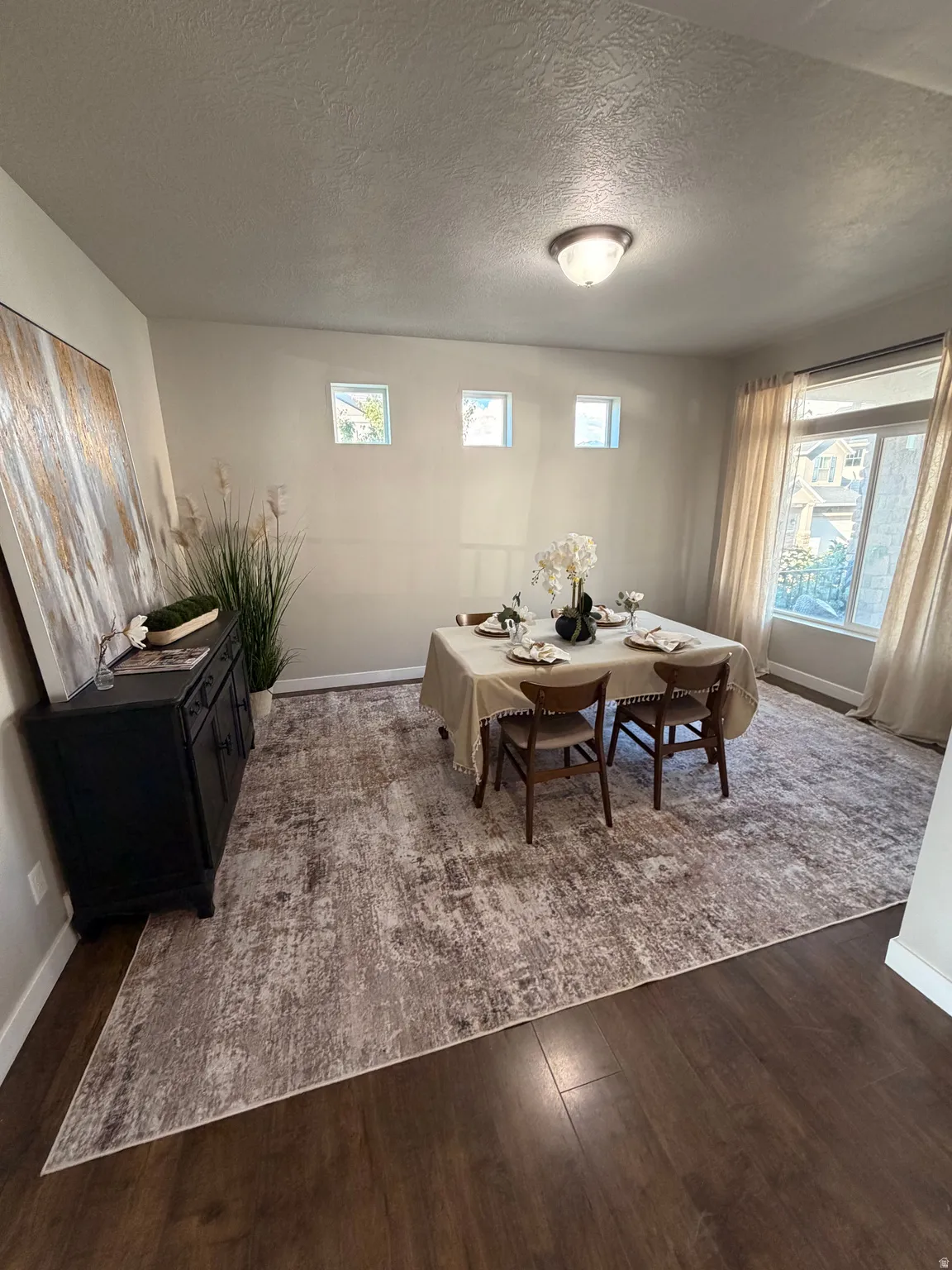 Formal dining area featuring rich wood-finish flooring, a large area rug, and recessed wall windows