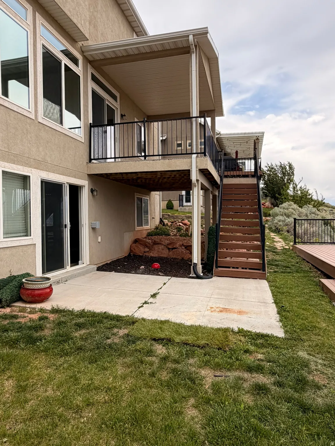 Multi-level outdoor living spaces featuring a covered upper deck with black metal railings, a lower covered patio, and a separate ground-level deck with matching railings