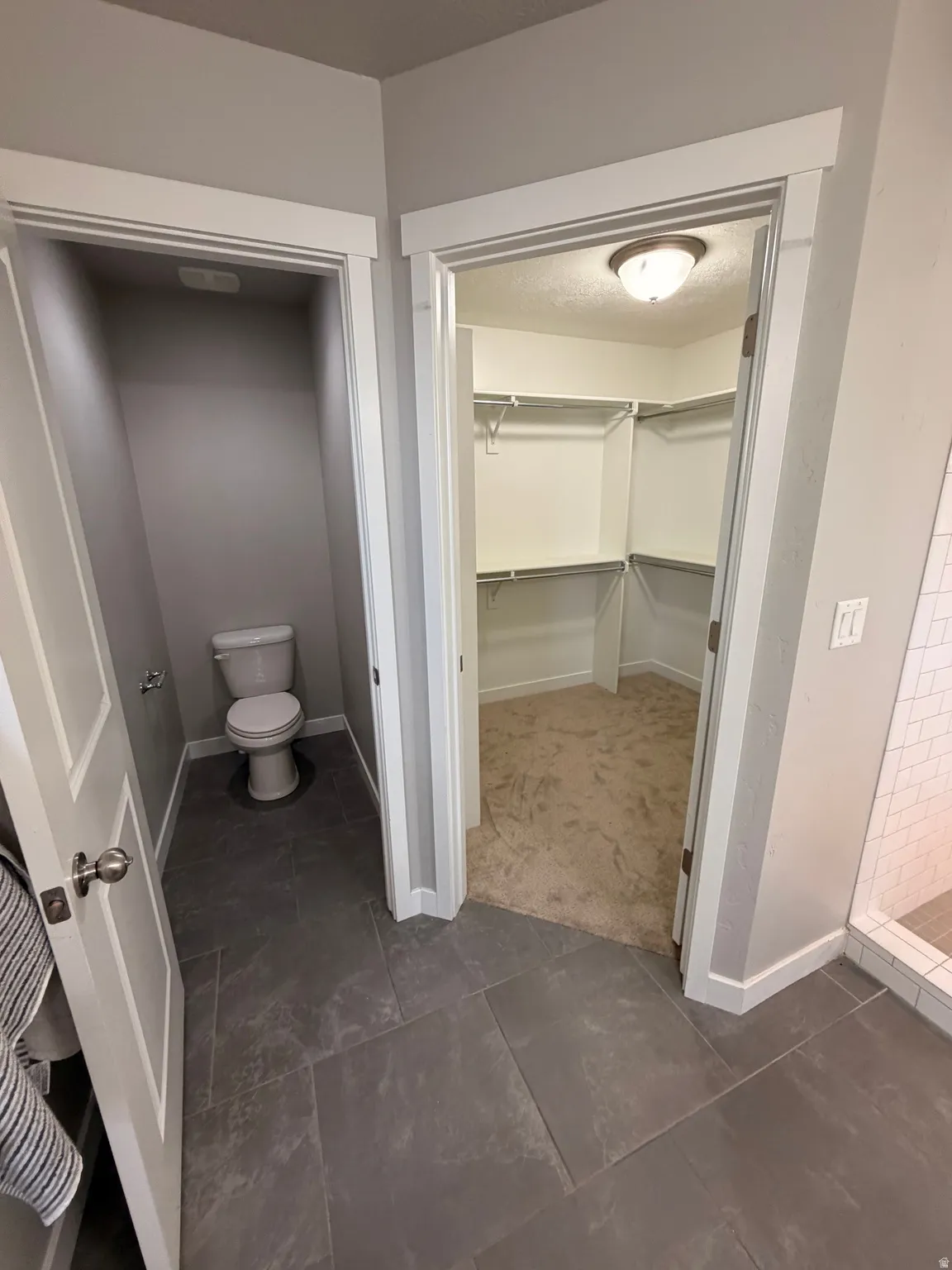 Dark gray tile flooring extending into a separate water closet