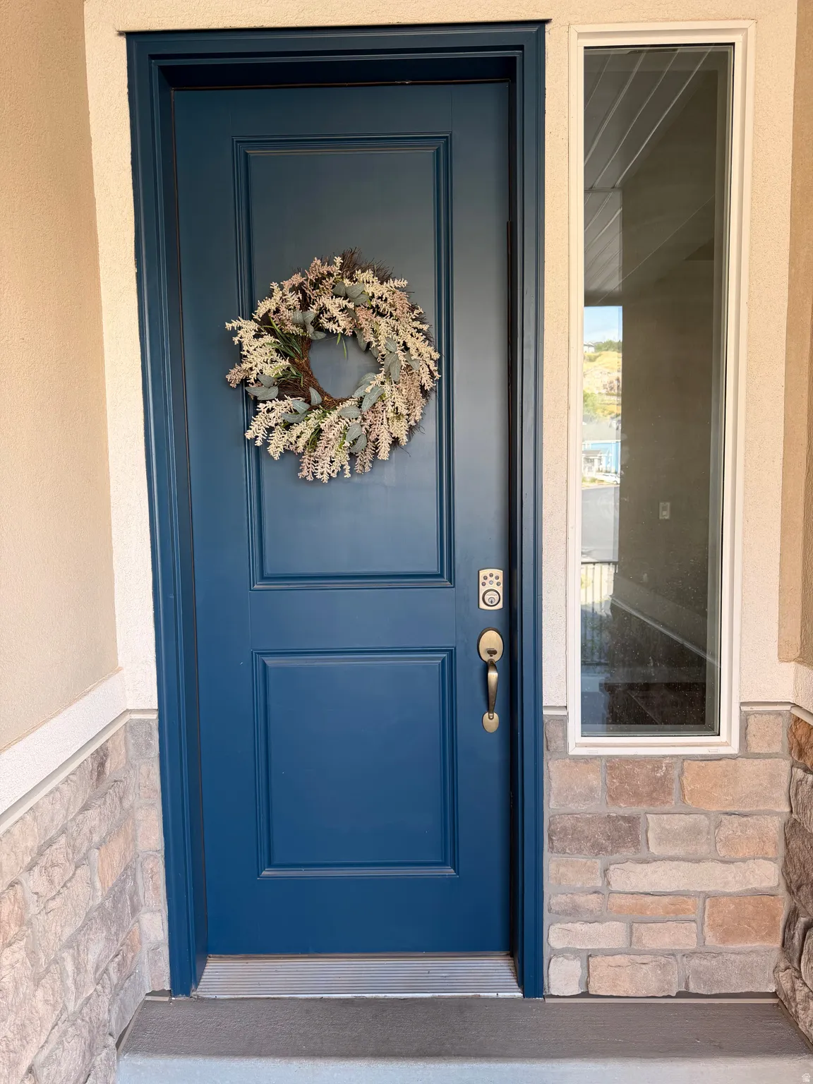 Blue paneled door with a brass handle and a digital keypad lock, complemented by a vertical sidelight window
