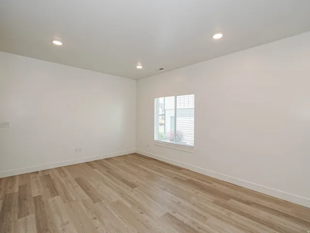 Bright interior room featuring wood-finish flooring, white walls, and recessed ceiling lighting