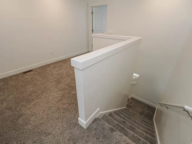 Upper landing with plush carpeting and a white painted half-wall railing