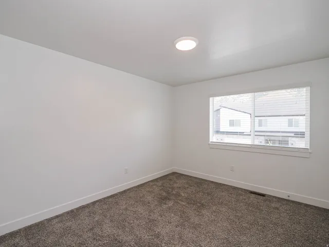 Neutral tone wall paint with white baseboards, a single window with blinds, and flush-mount ceiling lighting