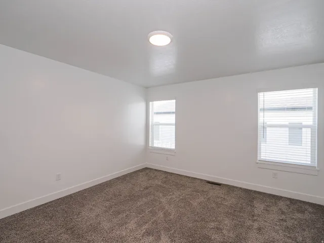 Spacious room featuring neutral carpeting and white painted walls