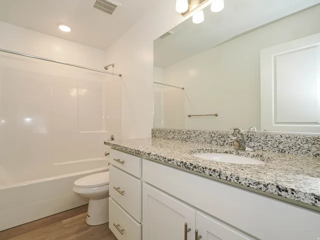 Bathroom featuring a white vanity with a speckled countertop, undermount sink, and brushed nickel fixtures