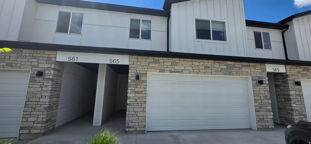 Modern townhome-style facade featuring stacked stone accents and vertical siding