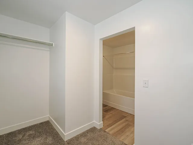 White walls and trim throughout, with a closet featuring a metal hanging rod