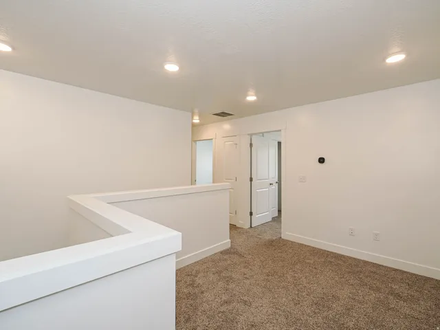 Carpeted common area featuring recessed lighting, a neutral color palette, white trim, and interior doors with black hardware