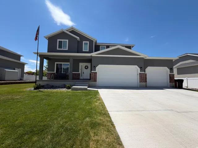 Two-story residence featuring a covered front porch with columns, a three-car garage, and a concrete driveway