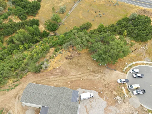 Property featuring a new construction residence with a shingle roof and metal roof accents, surrounded by undeveloped land
