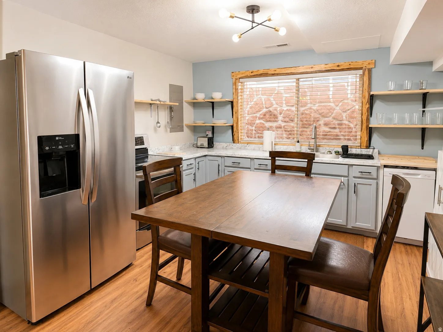 Basement Kitchen featuring wood-finish flooring, stainless steel appliances, light gray cabinetry with white countertops, and a wood-framed window