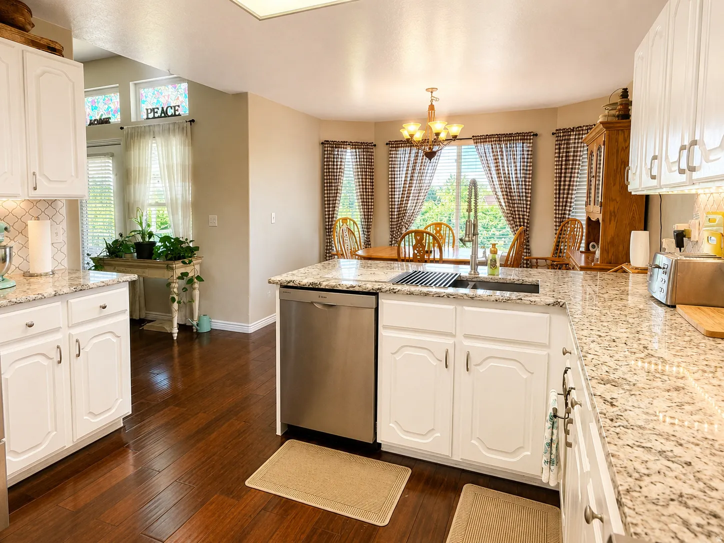 Kitchen featuring bamboo flooring, white cabinetry, a light-toned backsplash, granite countertops, and stainless steel appliances