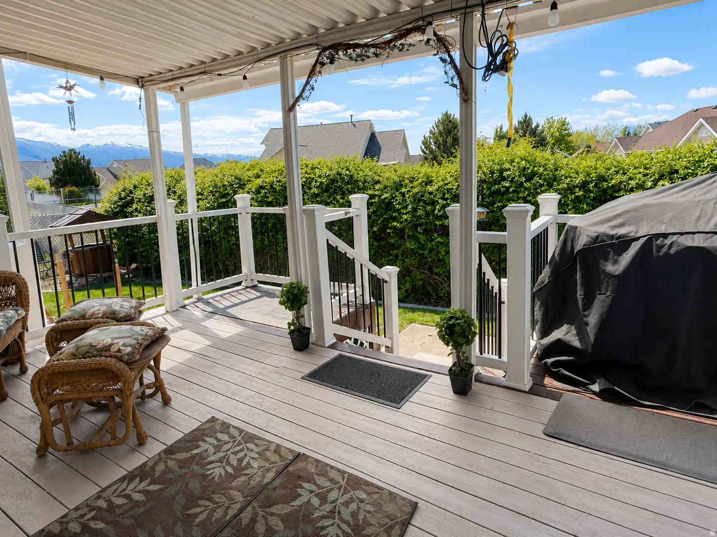 Covered outdoor deck featuring composite decking, white railing with black spindles, and mountain scenery