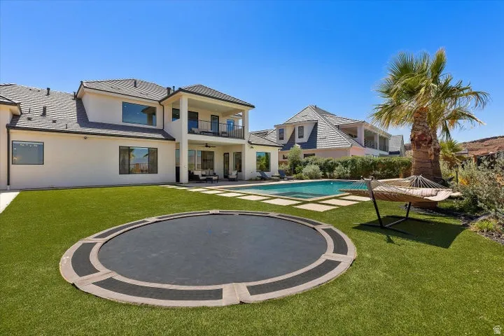 Expansive backyard featuring a rectangular swimming pool, integrated stepping stone pavers, and a manicured artificial turf lawn