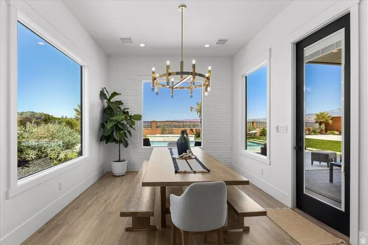 Dining space featuring light wood-finish flooring, white walls, and a prominent gold-toned chandelier