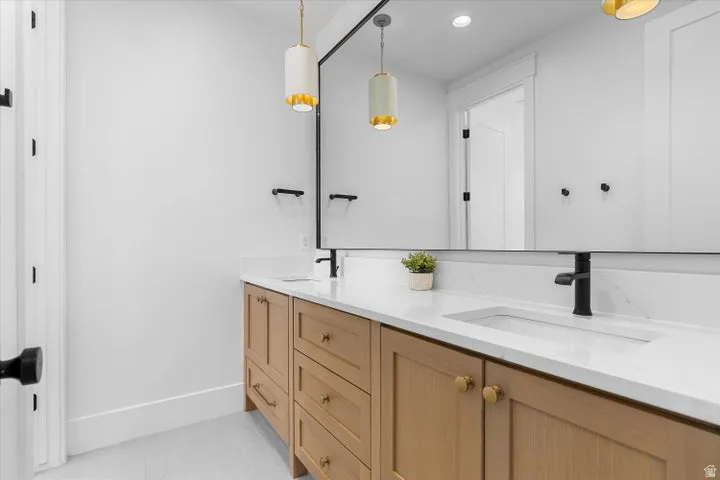 Double vanity with natural wood-finish cabinetry, integrated sinks, and quartz countertops