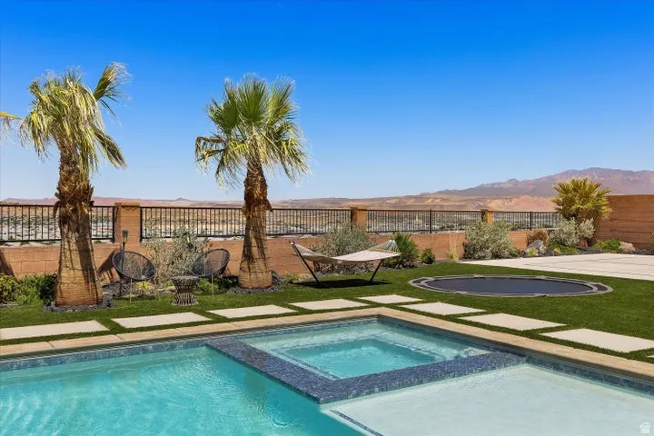 Outdoor living space featuring a blue-tiled swimming pool with an integrated spa