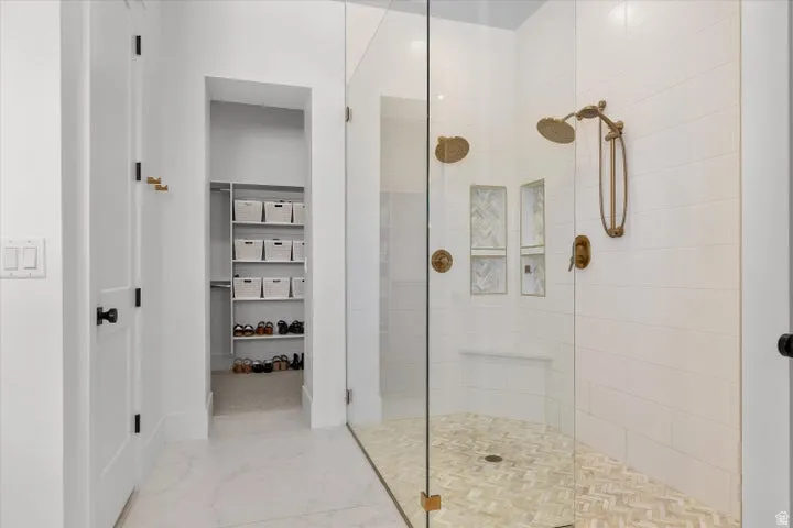 Contemporary walk-in shower featuring a glass enclosure, dual shower heads with gold-tone fixtures, and a herringbone-patterned floor