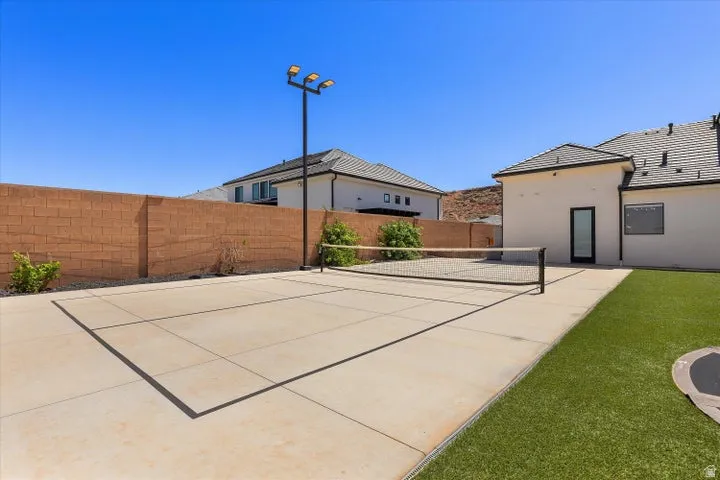 Outdoor court with integrated lighting, bordered by a block wall and artificial turf