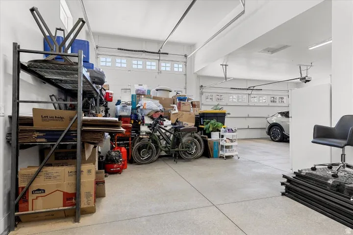 Spacious garage with light grey concrete flooring, multiple overhead garage doors, and white walls
