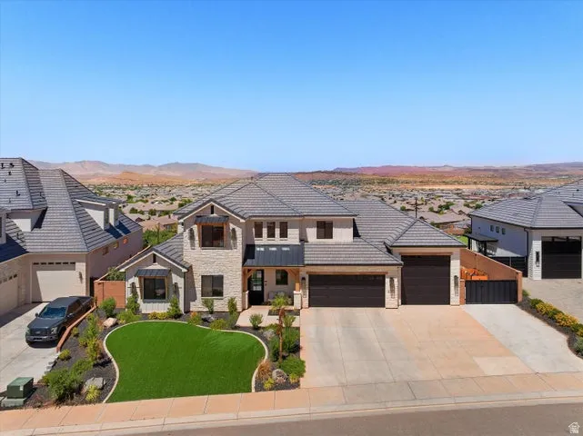 Contemporary residence featuring stone and stucco exterior, a multi-car garage, and a tiled roof