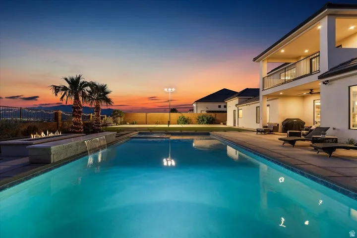 Expansive outdoor living area featuring a rectangular swimming pool, concrete patio, and an integrated fire pit