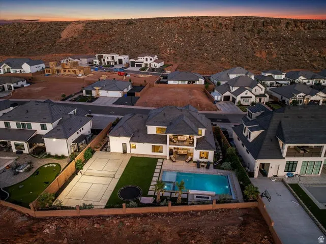Rear property featuring a rectangular pool, integrated spa, turf lawn, and a fenced sports court