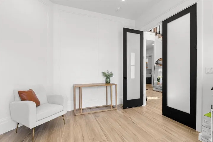 Entryway featuring wood-finish flooring, wainscoting, recessed lighting, and black-framed frosted glass doors
