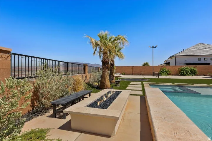 Backyard oasis featuring a rectangular swimming pool with integrated spa, a linear fire pit with black fire glass, and a surrounding patio