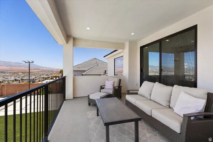Covered balcony featuring recessed lighting, a black metal railing, and a sliding glass door