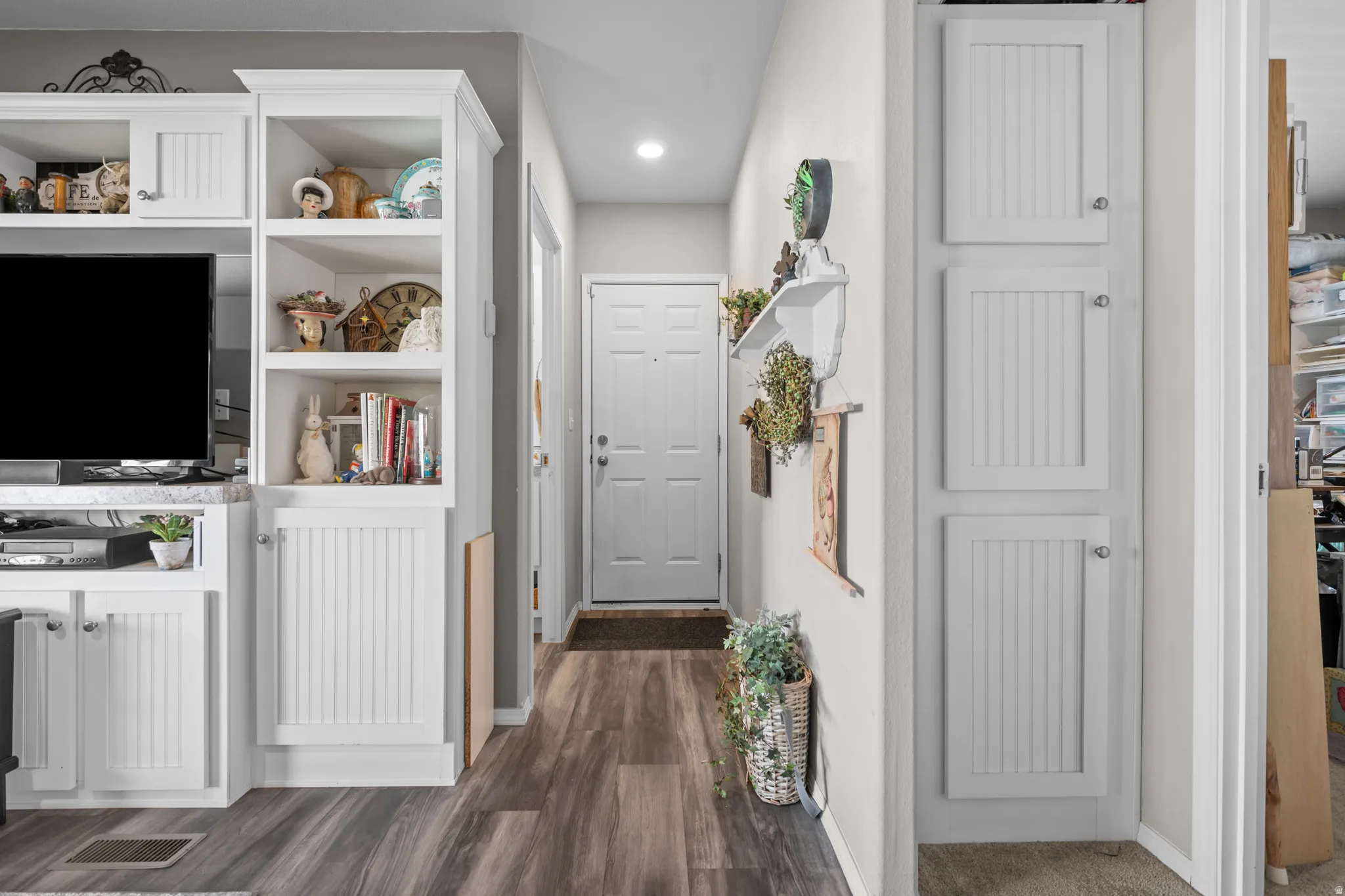 Wood-finish flooring throughout, complemented by a white paneled entry door and recessed ceiling lighting