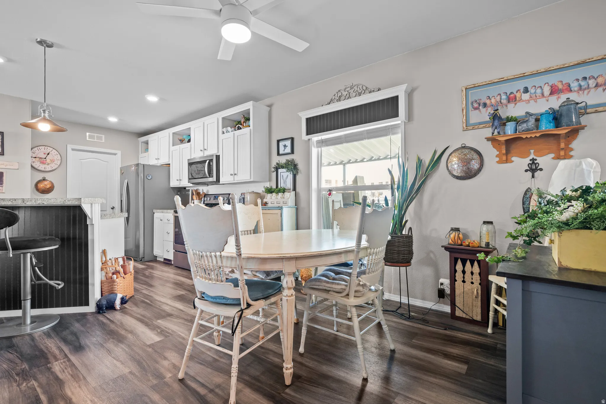 Open-concept kitchen and dining area featuring wood-finish flooring, white cabinetry, and granite-look countertops
