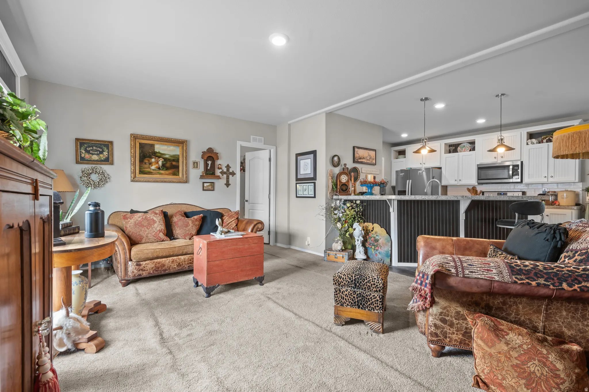 Expansive open-concept living space with light gray wall tones and neutral carpeting