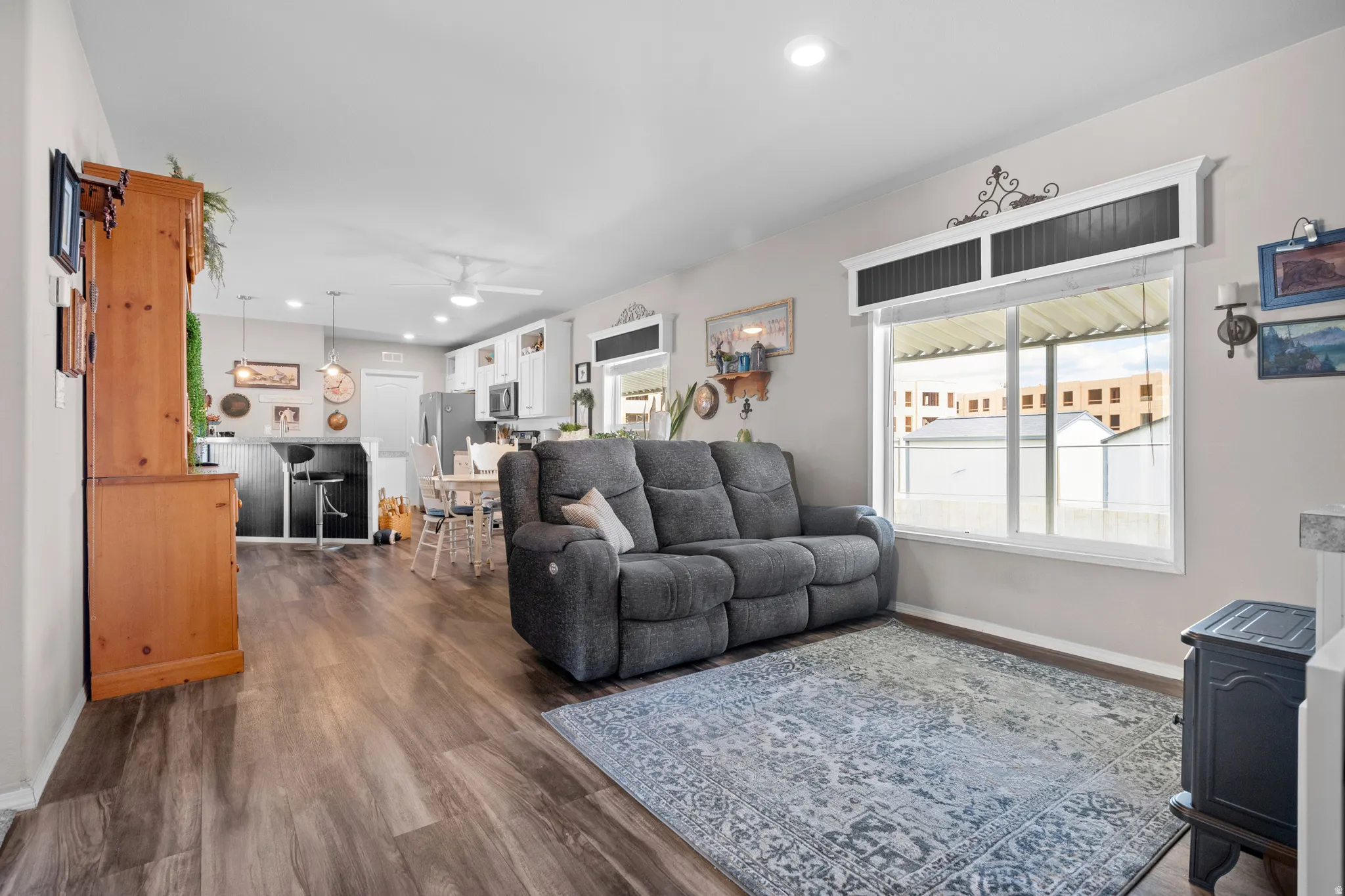 Open-concept living area featuring wood-finish flooring, recessed lighting, and a large window with custom trim