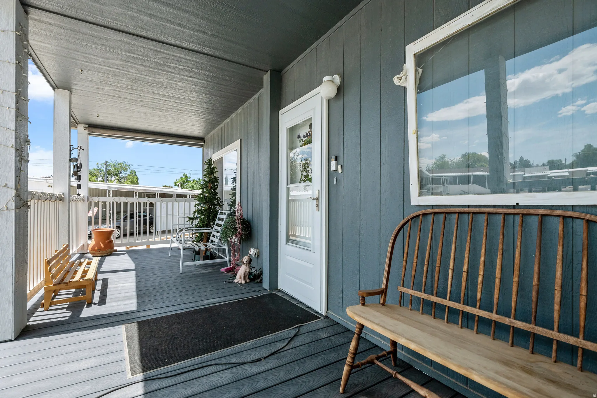 Covered porch featuring gray wood-finish decking, white railings, and a light blue exterior wall