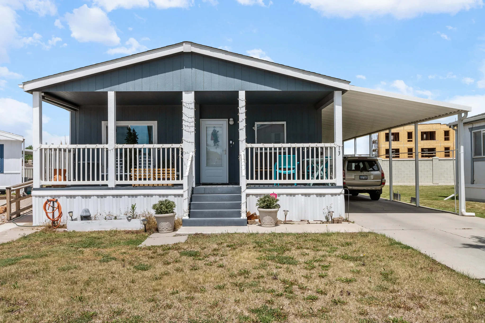 Single-story residence featuring a covered front porch with white railing, a carport, and a light blue exterior siding