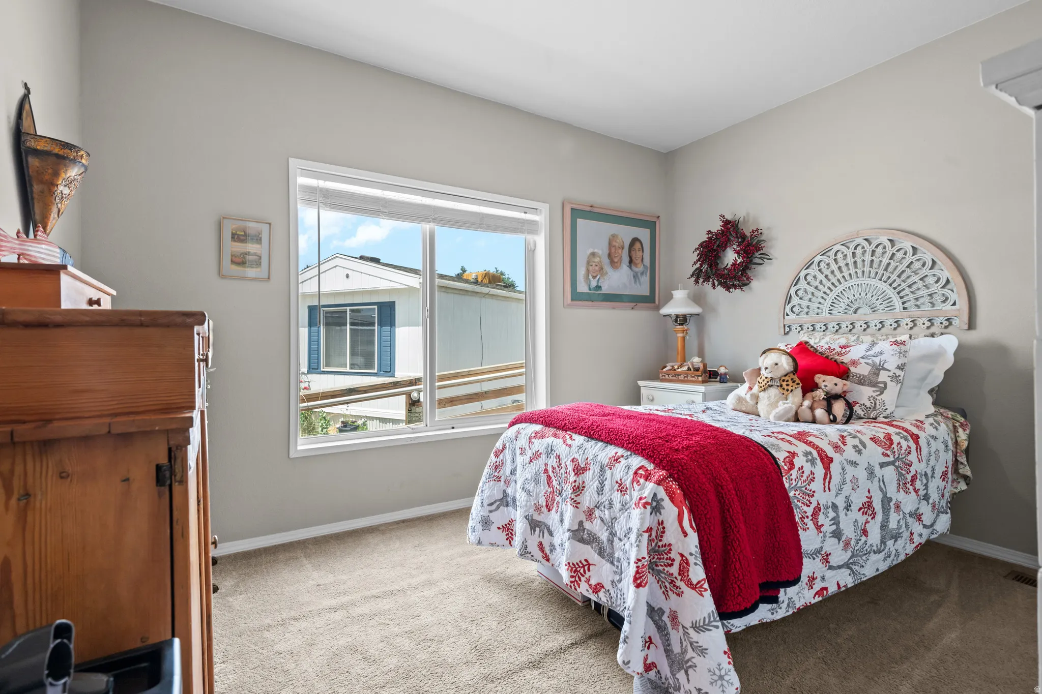 Bedroom featuring neutral wall paint, carpet flooring, a white window frame, and a decorative headboard