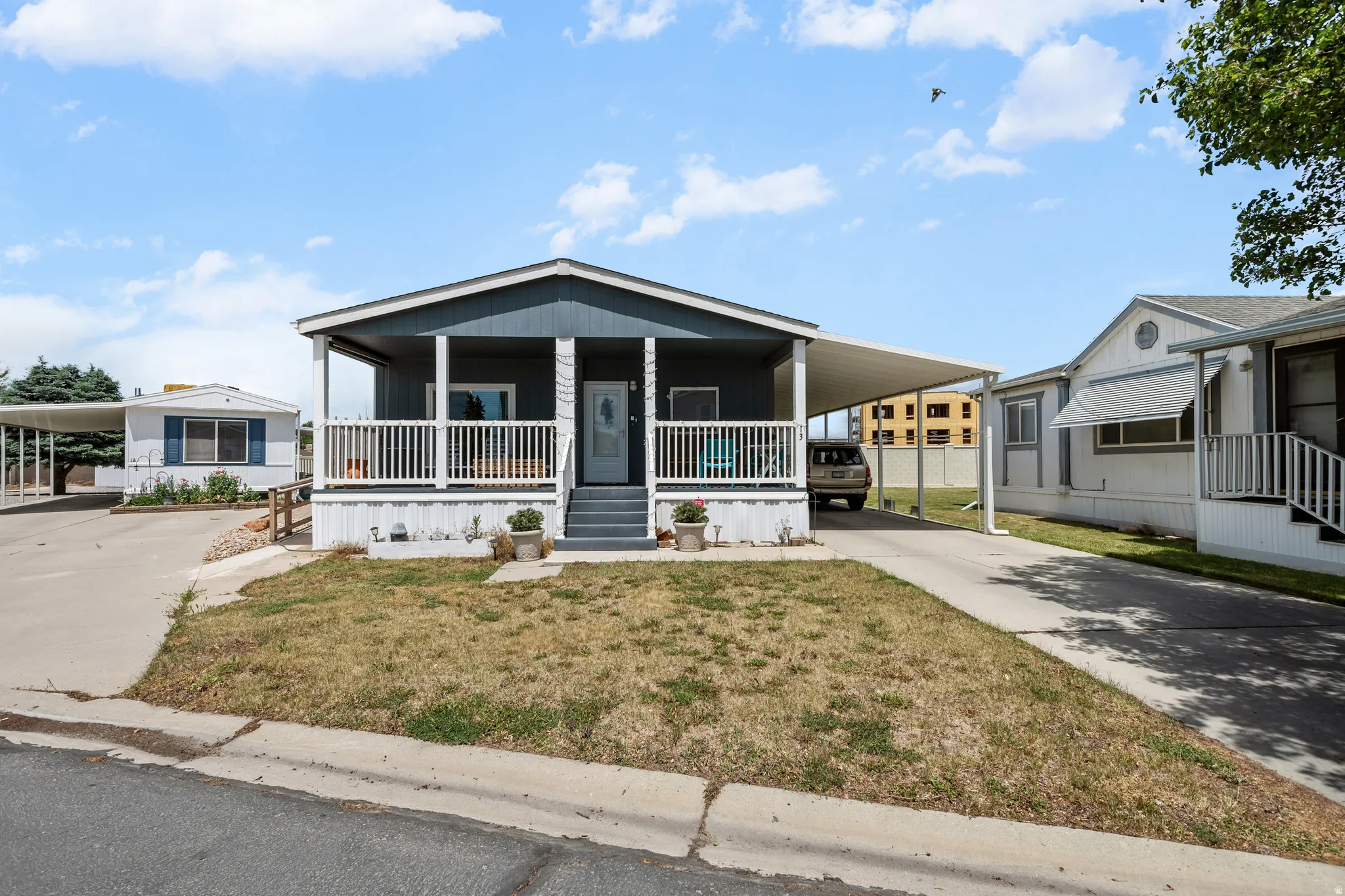 Dark blue siding exterior with a white-railed front porch and covered carport