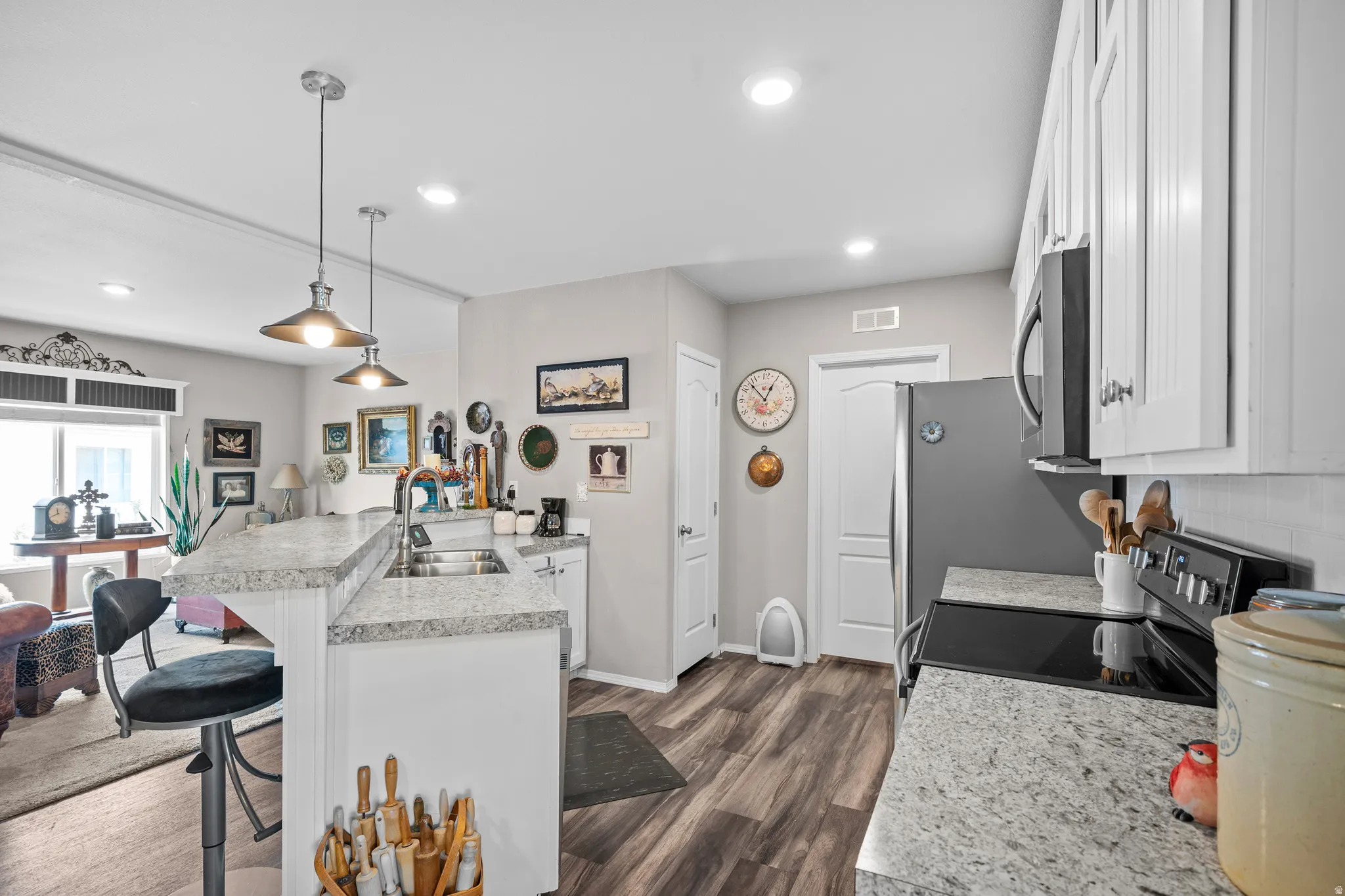 Kitchen featuring light-colored cabinetry, speckled countertops, and wood-finish flooring