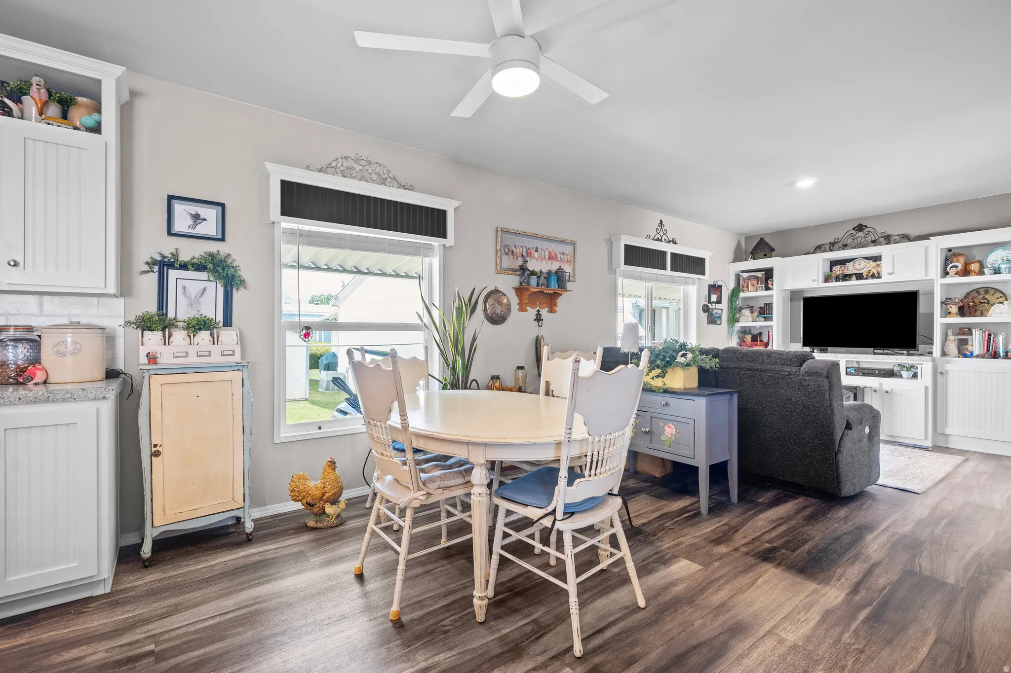 Open-concept living area featuring wood-finish flooring, a ceiling fan, and white built-in cabinetry