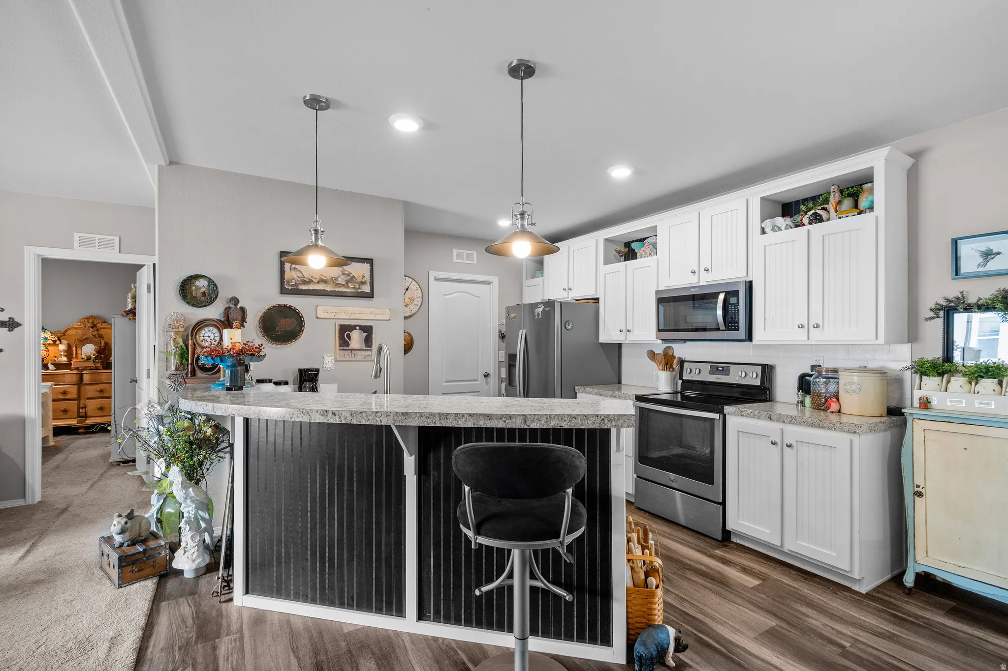 Kitchen with wood-finish flooring, white cabinetry, and light-toned countertops