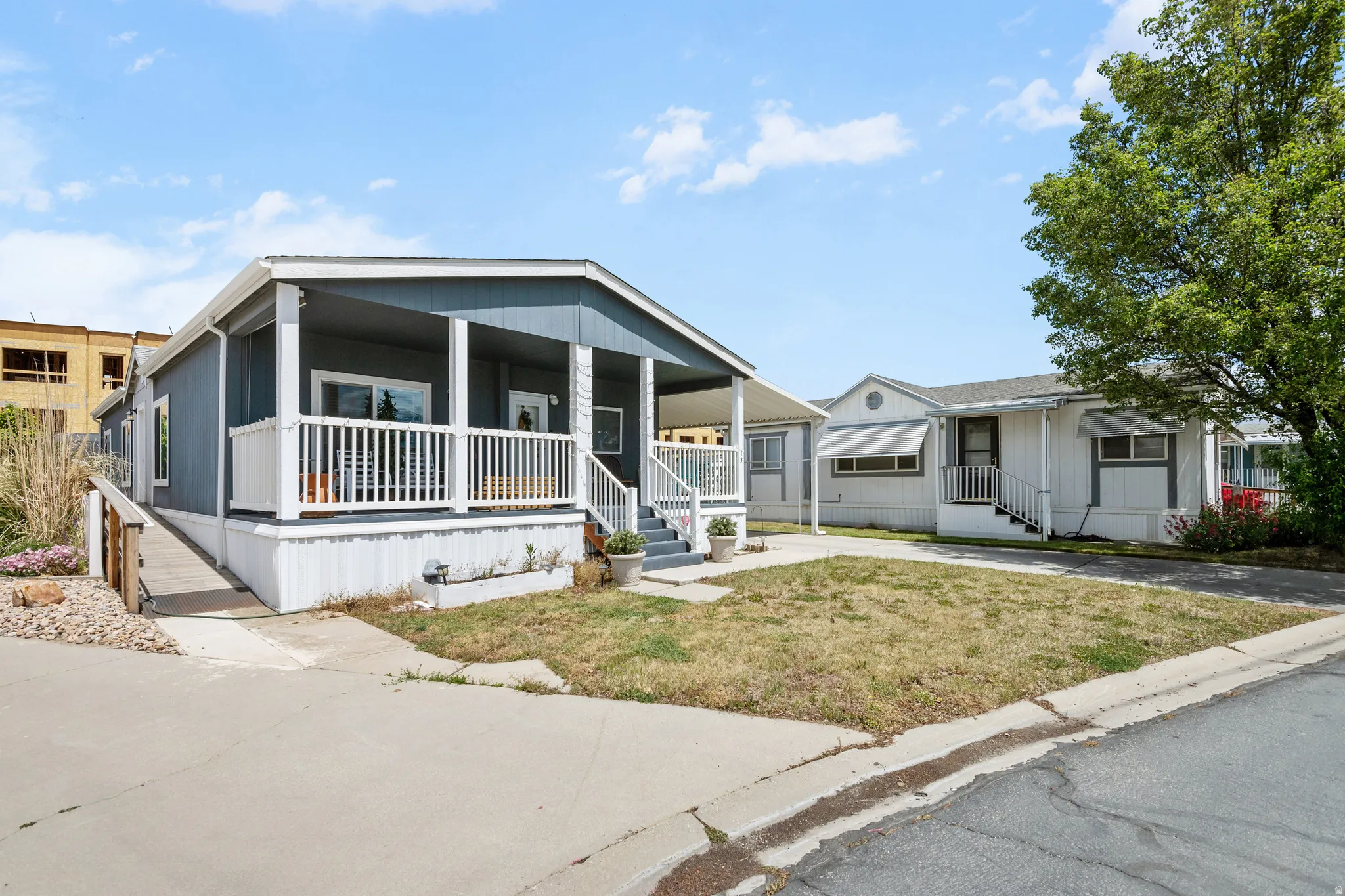 Exterior siding with a covered porch featuring white railing, an accessible ramp, and a carport