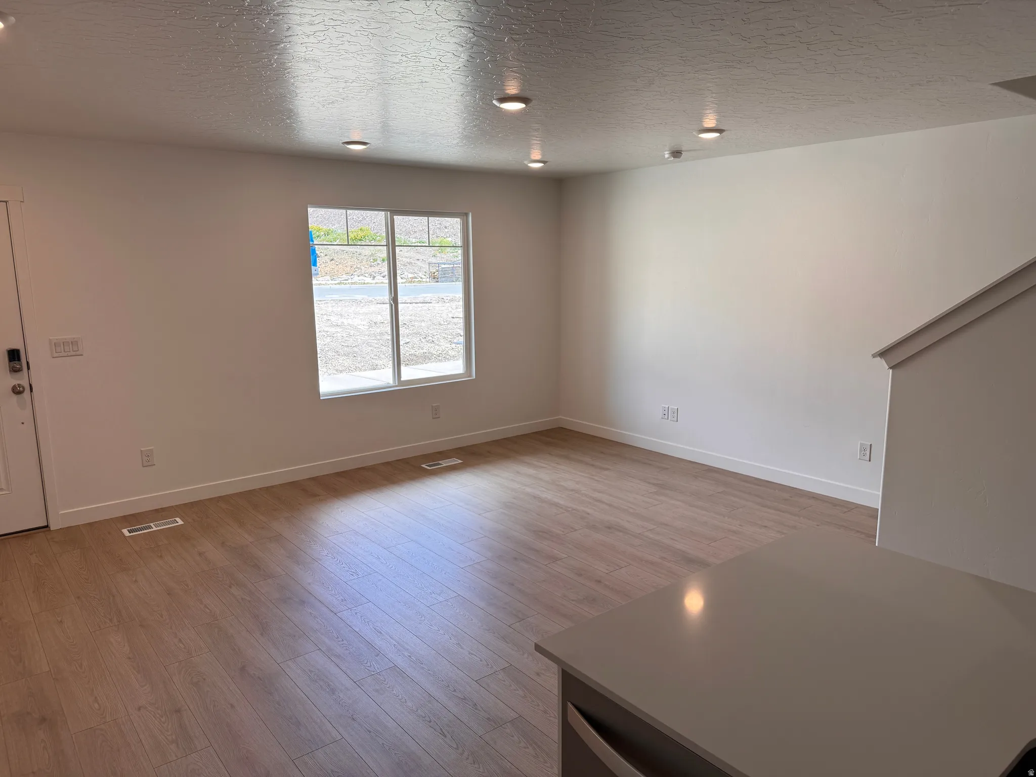 Open-concept living area featuring light wood-finish flooring, recessed ceiling lighting, and a neutral color palette